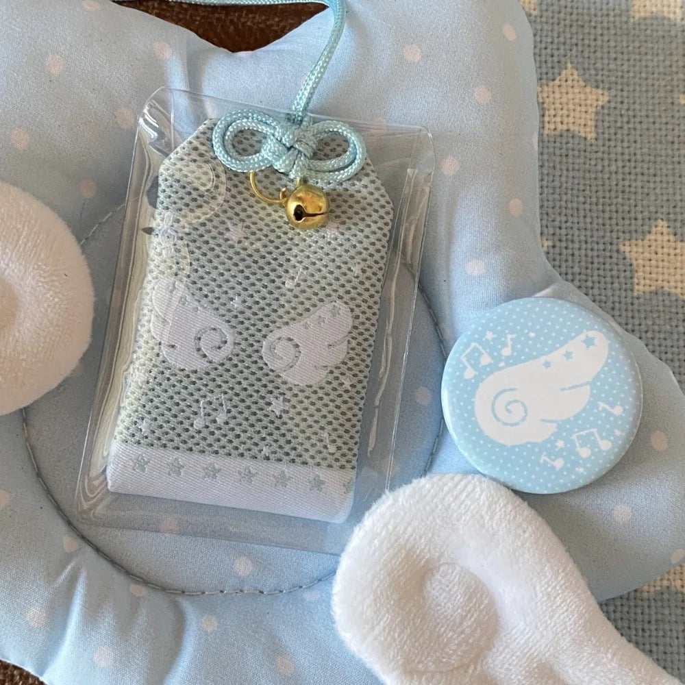 A light blue mesh diy embroidery blessings charm with musical notes wings, white embroidery, gold bell, and ribbon gift keyring