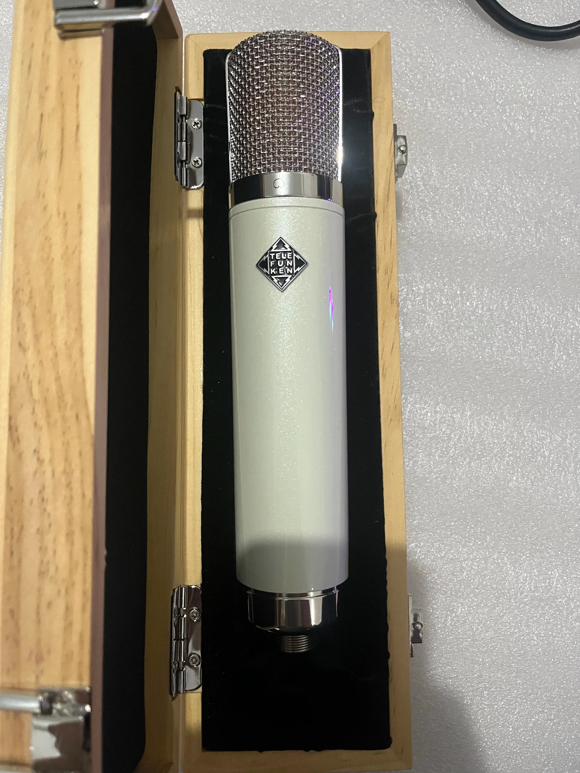A sleek cream-colored neumann u87 ai vacuum tube microphone with metallic mesh grille and cardioid pickup for professional recording studios
