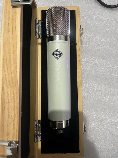 A sleek cream-colored neumann u87 ai vacuum tube microphone with metallic mesh grille and cardioid pickup for professional recording studios