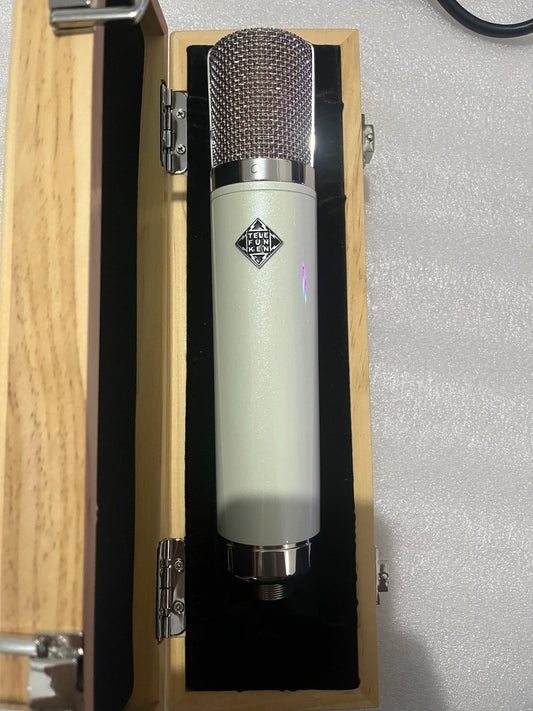 A sleek cream-colored neumann u87 ai vacuum tube microphone with metallic mesh grille and cardioid pickup for professional recording studios
