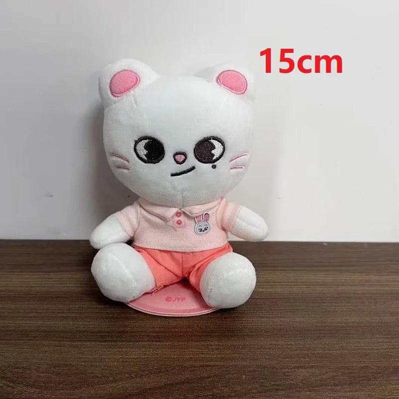 A 15cm white plush cat toy wearing light pink polo shirt and coral shorts skzoo plush keychain magic academy cloak toy fan gift
