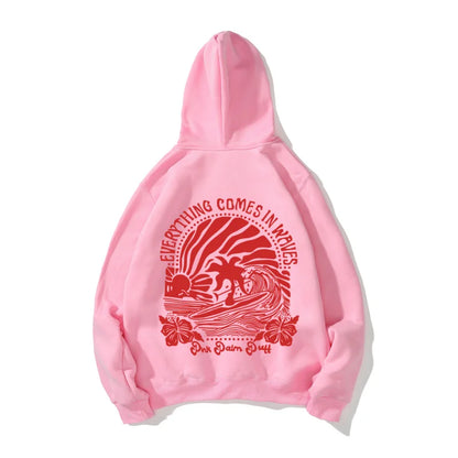 Pink hoodie with red graphic print of palm trees and waves and text everything comes in waves pink palm duff youth tropical flower