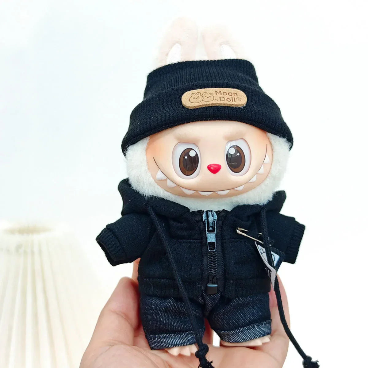A cute plush doll wearing a black knit beanie with tan leather moon doll logo patch in a black suit fashion outfit for labubu clothes gifts