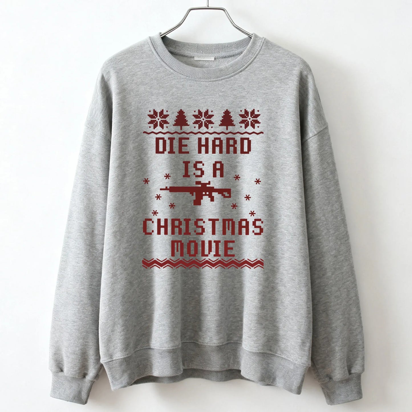 Gray unisex sweatshirt with red pixelated die hard mclane naktomi plaza text snowflakes trees and rifle graphic