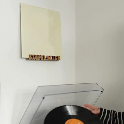Beige vinyl record album mounted on wall with solid wood album now playing record stand display shelf beneath it