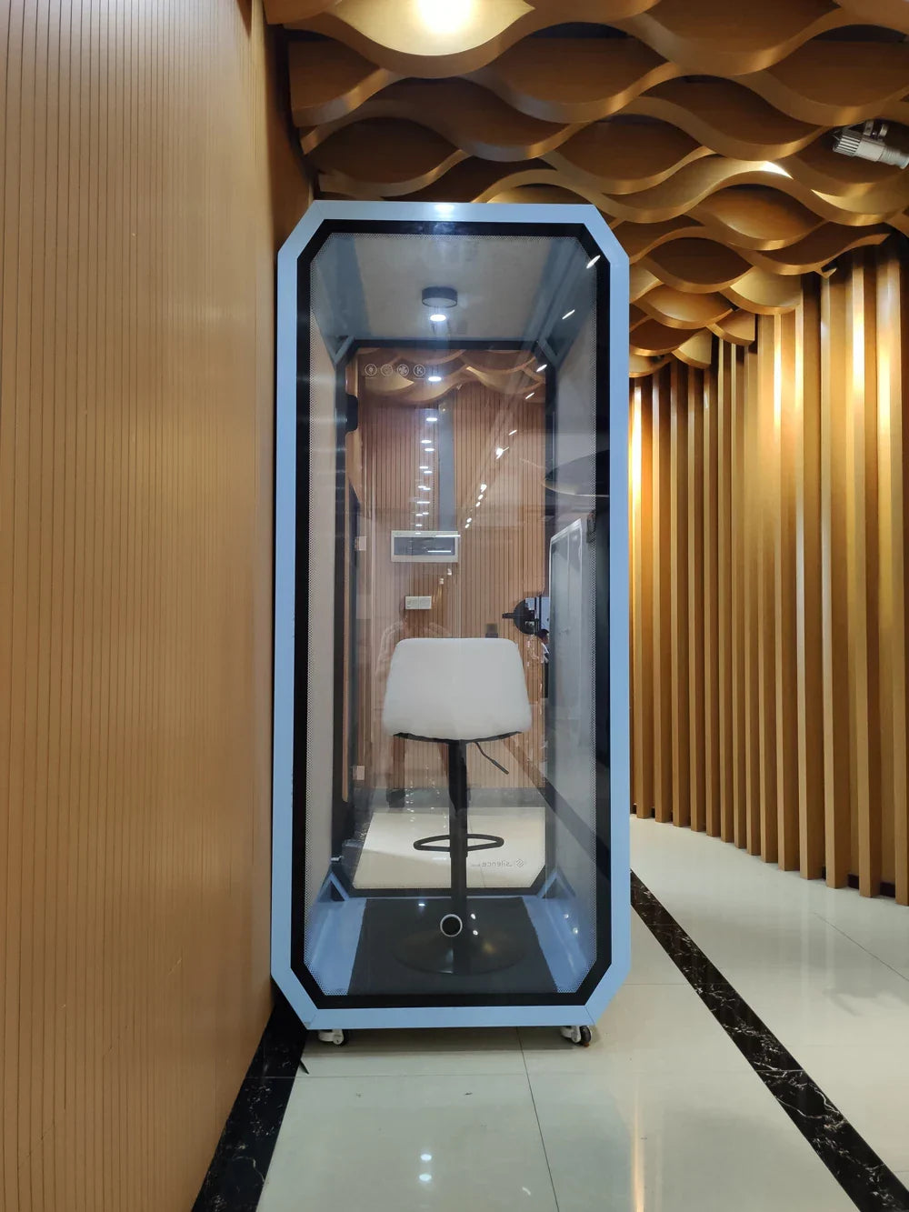 Light blue-framed transparent glass office pod soundproof booth with a white stool for pod soundproof outdoor meetings