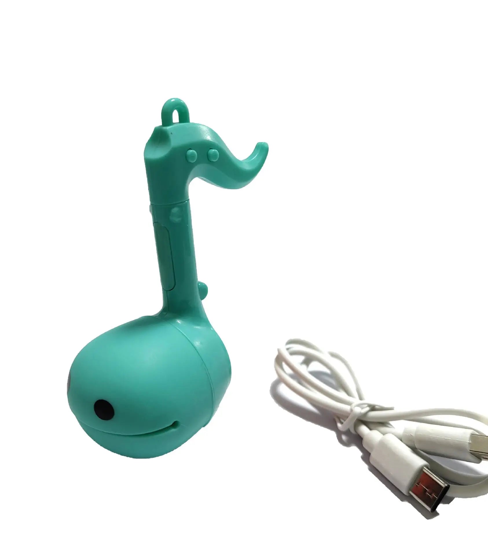 Teal-colored plastic otamatone mini electronic musical toy shaped like a musical note with a smiling face and button details
