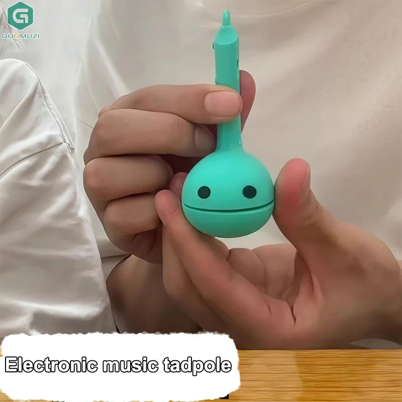 A teal otamatone mini electronic music toy with rounded body and simple eyes for soothing relaxing musical play
