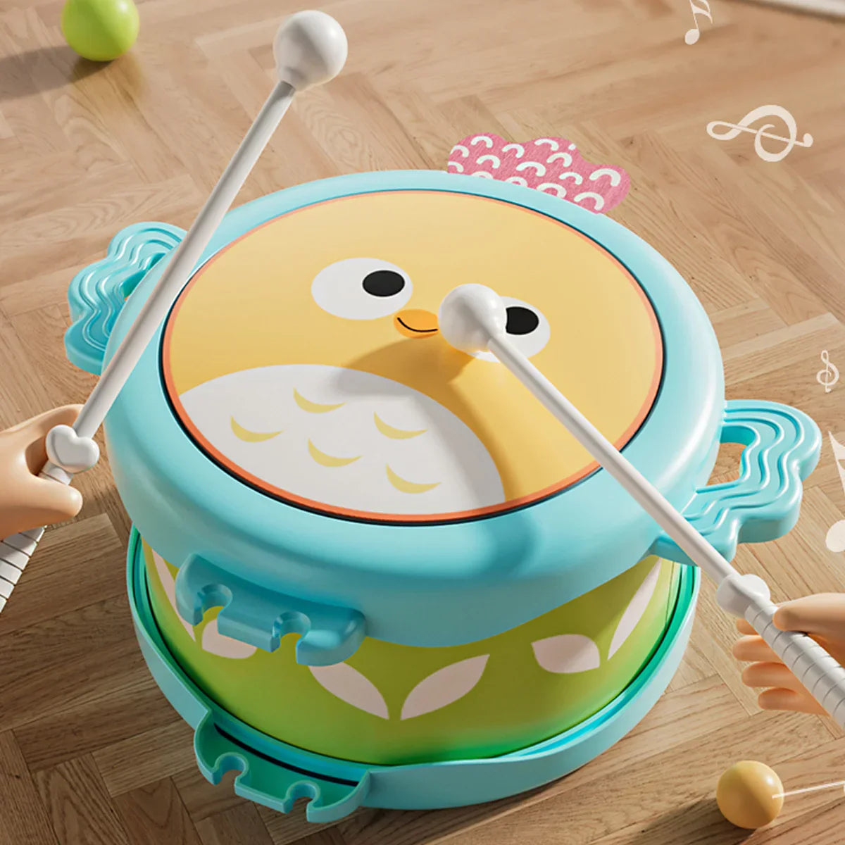 A cheerful turquoise and green owl double sided drum plastic education musical instrument for motor skills hand coordination