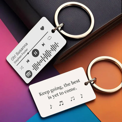 Two silver-toned rectangular personalized custom spotify code keychains engraved with song details and motivational blessings stainless steel rings