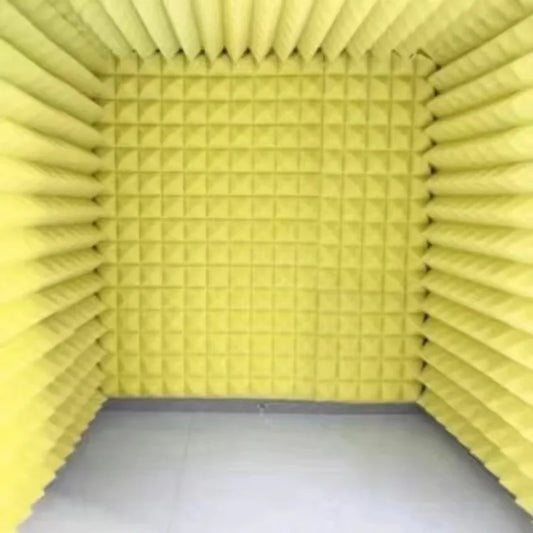 Yellow acoustic foam panels with triangular indentations form a portable desktop recording studio noise reduction chamber for reading sound insulation