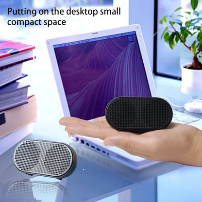 Black oval-shaped portable mini speaker with perforated grille and rounded edges offers good performance for laptops