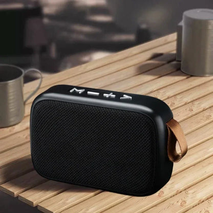 Black portable mini oxford loudspeaker with textured fabric grille silver buttons and tan leather strap for outdoor use