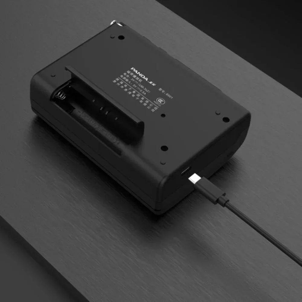 Black panda jw battery charger with usb-c cable connected to the back of a portable radio retro cassette walkman tape recorder