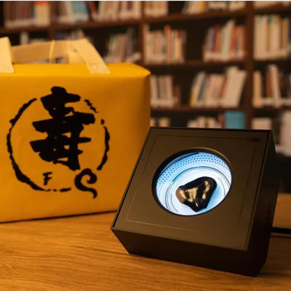 Black rectangular display case with circular illuminated window showcasing dark glossy mineral for portable visual music venom sensor ferrofluid magnetic use