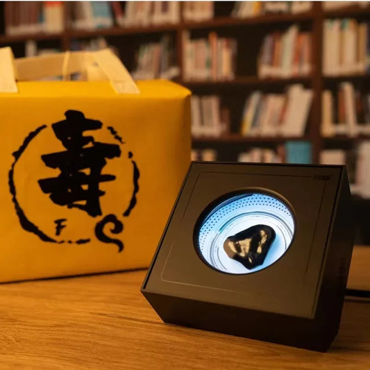 Black rectangular display case with circular illuminated window showcasing dark glossy mineral for portable visual music venom sensor ferrofluid magnetic use