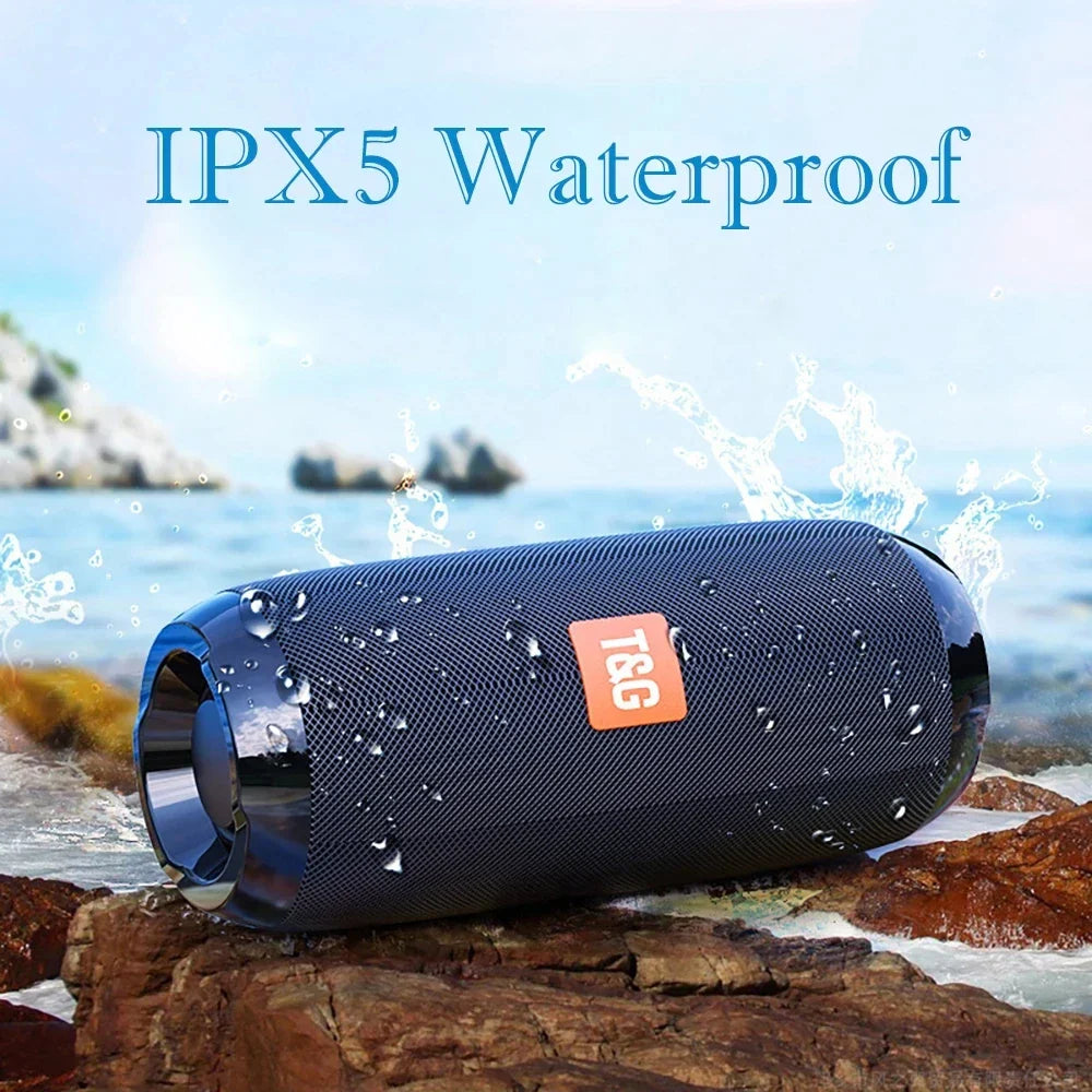 Black textured jbl portable wireless bluetooth speaker with orange logo waterproof on rocks by ocean for radio fm handfree use