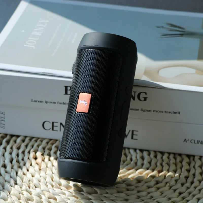 Black cylindrical portable wireless bluetooth speaker with textured surface and orange play button supports tf card easy carry