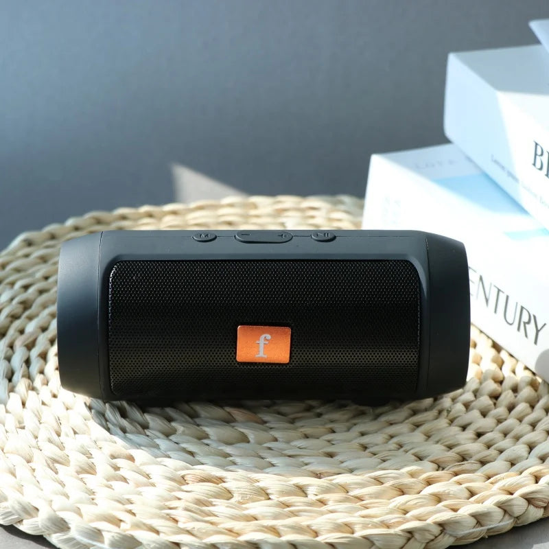 Black portable wireless bluetooth speaker with orange logo and textured grille supports tf card and easy carry feature