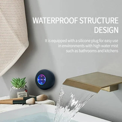 Black circular portable wireless bluetooth speaker with ipx4 waterproof rating and suction cup mounted near faucet