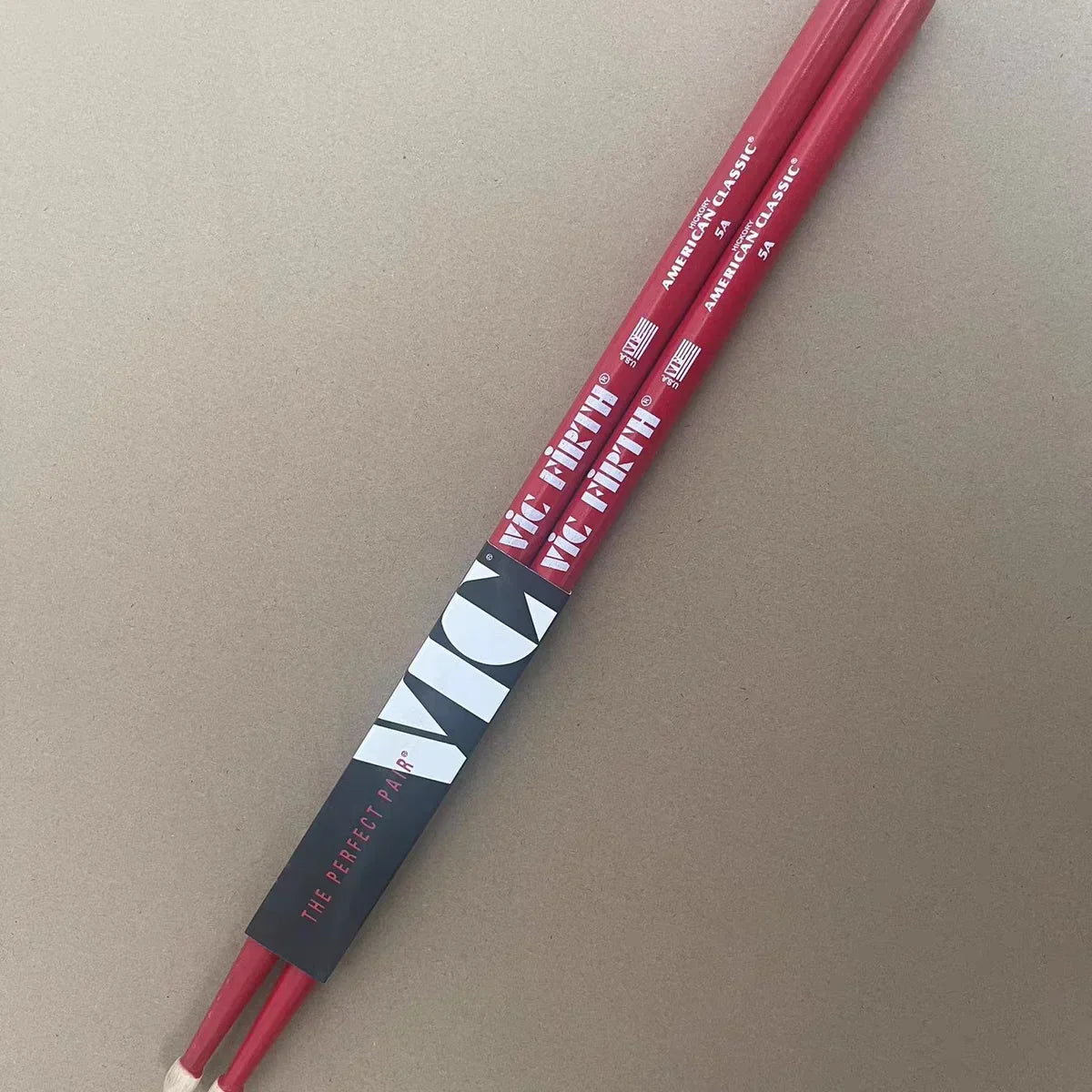 Red professional vic firth drumsticks with white branding and a black band labeled the perfect pair for jazz rock durable use