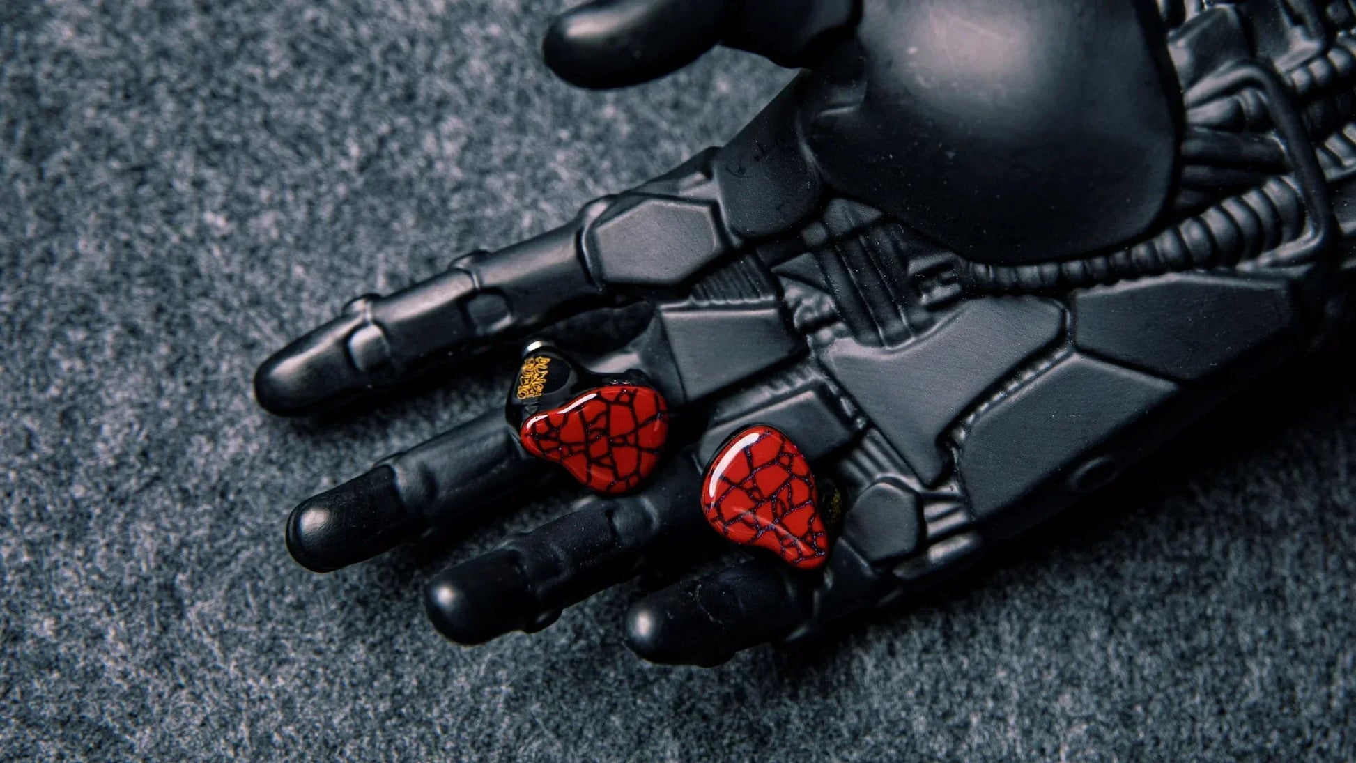 Red heart-shaped punch audio martilo iem with planar drivers and custom interchangeable cable on black robotic hand