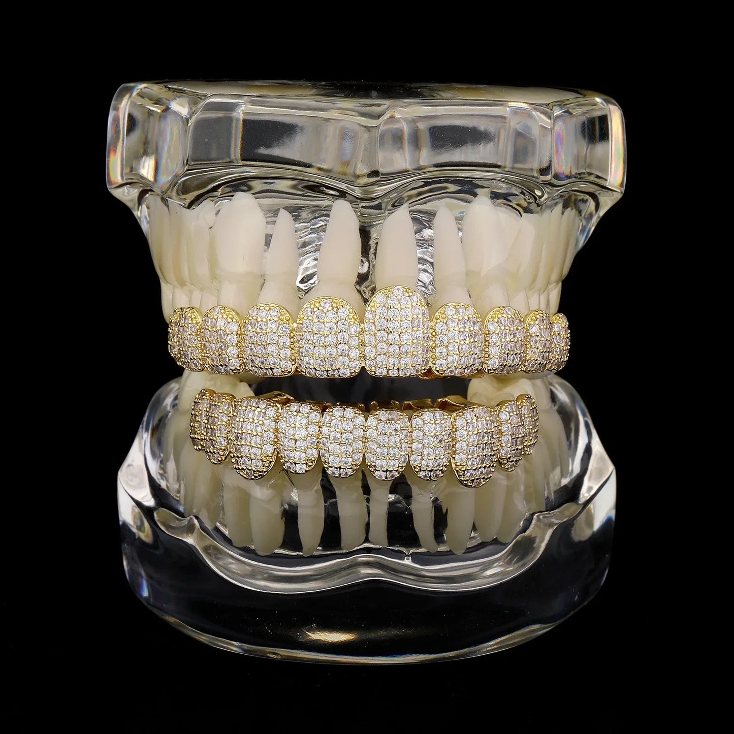 Gold-plated diamond-encrusted stone teeth grillz displayed in a clear dental model featuring zirconia tooth caps for men and women
