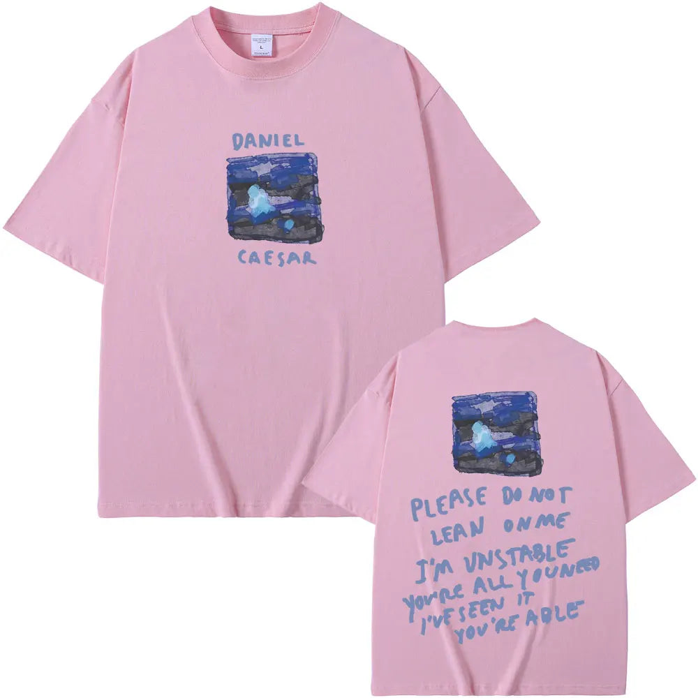 Pink short-sleeved t-shirt with blue abstract graphic and rapper daniel caesar text for women hip hop fashion