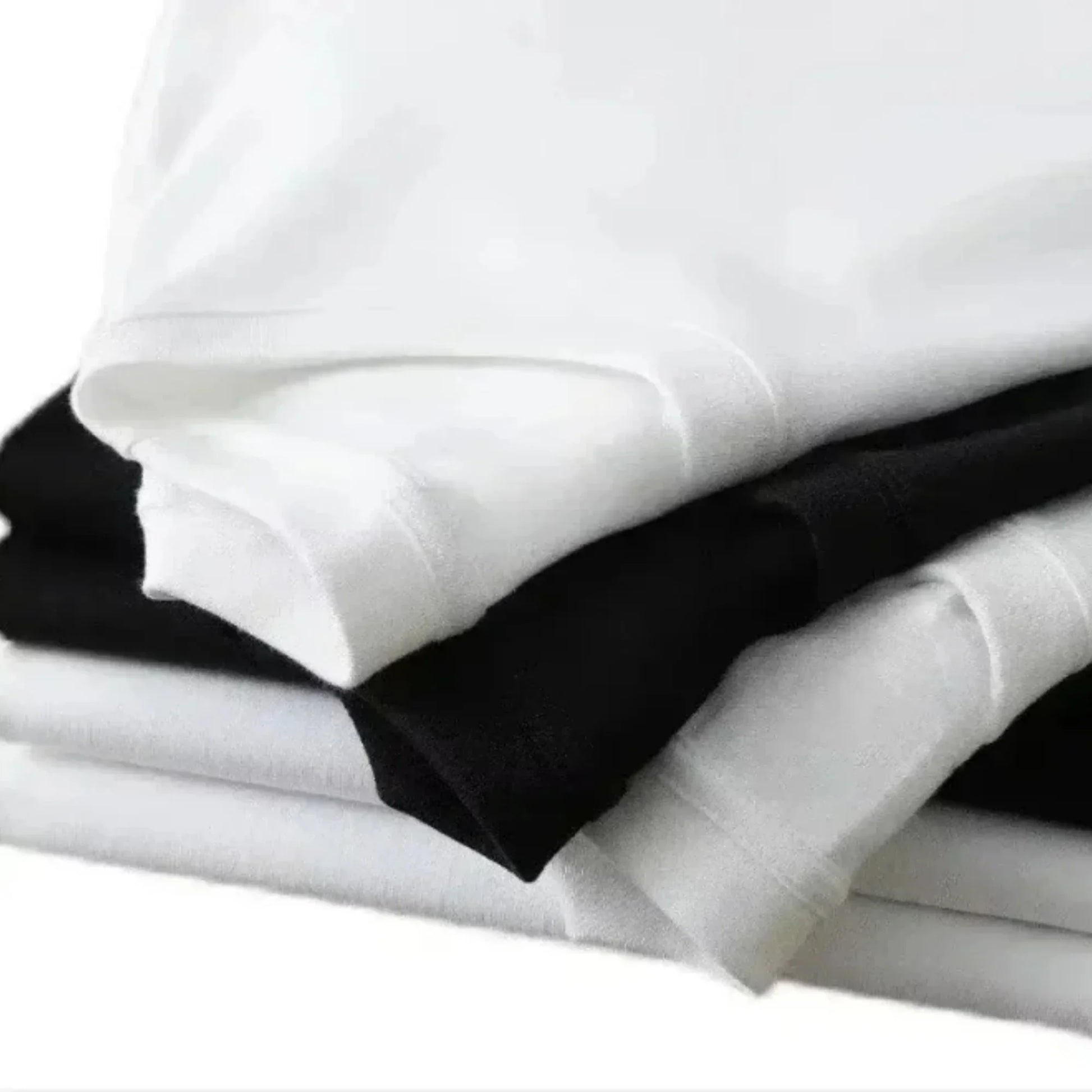 Stack of neatly folded white and black casual cotton short sleeve oversized rapper jul graphic hip hop y2k t-shirts
