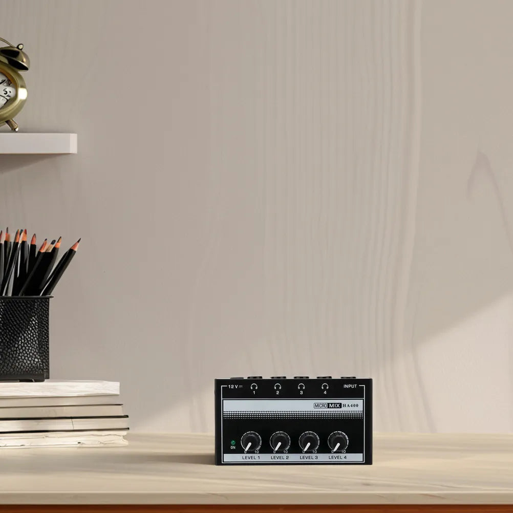 Black rectangular metal recording studio headphone amplifier with four level knobs and top input jacks for office splitter