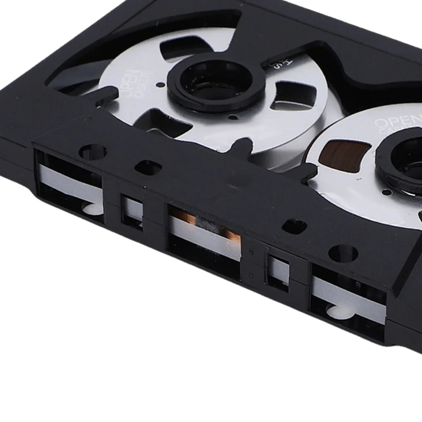 Black plastic blank cassette tape with silver metal spools and visible magnetic sound recording tape for music and speech