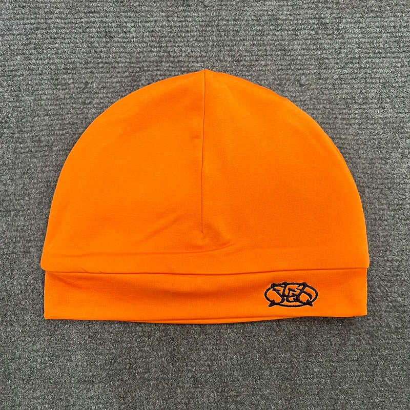 Bright orange knit pullover hat trendy with black embroidered letter cap on folded brim for fashionable streetwear
