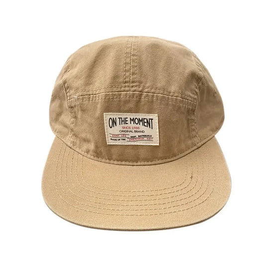 Beige five-panel baseball cap with flat brim and white on the moment label, quick-drying breathable sunscreen hat