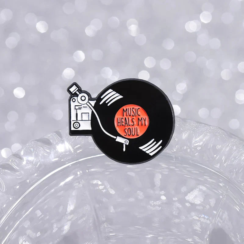 Black enamel pin featuring a retro music records design with an orange center reading music heals my soul for soul brooches lapel