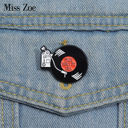 Black enamel retro music records pin featuring a vinyl record with music heals my soul text and white turntable design