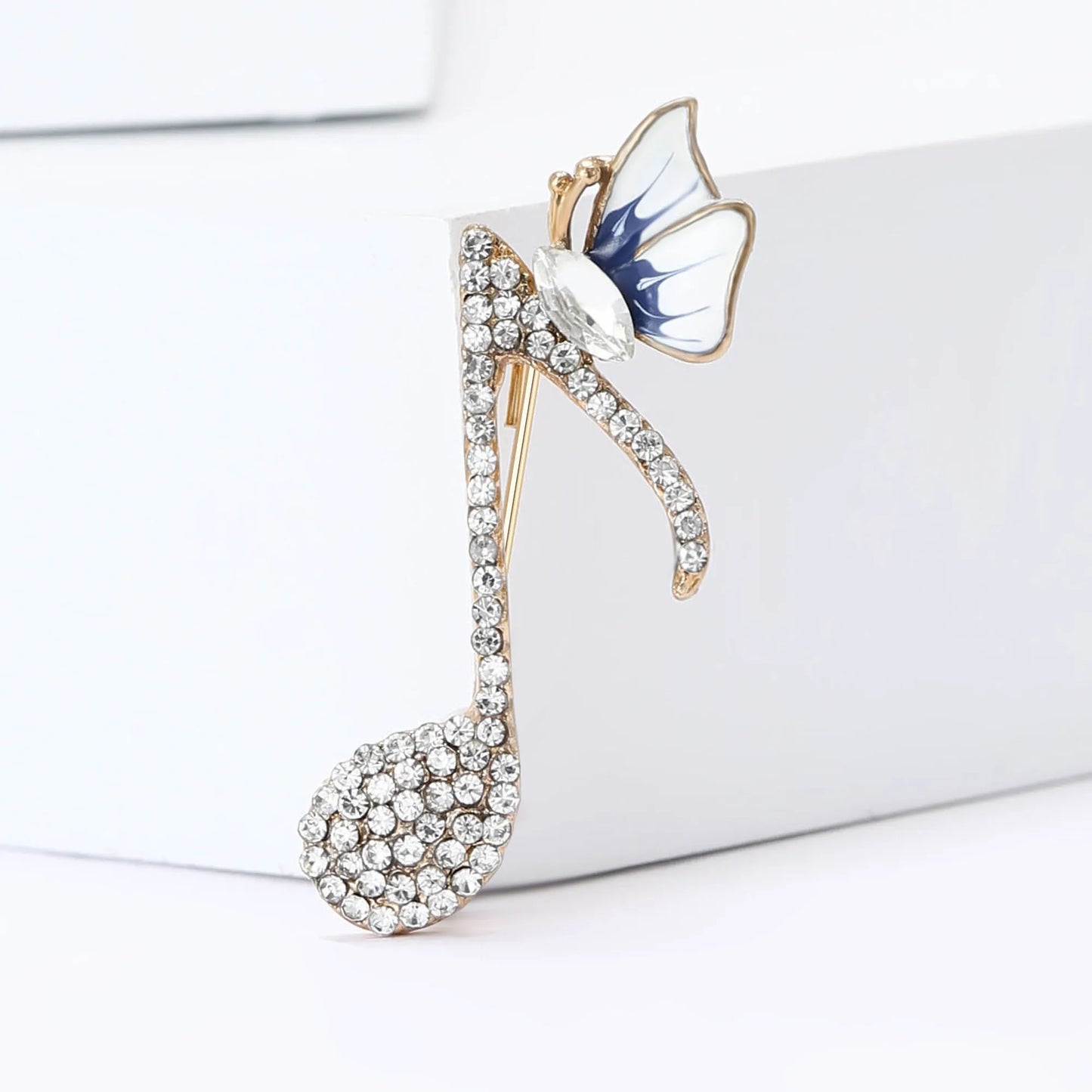 A gold-tone rhinestone butterfly pin with clear crystals and blue-white enamel for event party backpack decoration