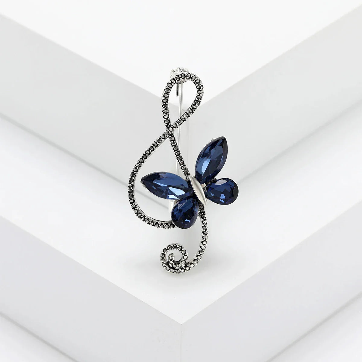 A navy blue rhinestone butterfly pin featuring a silver-toned shiny glass musical treble clef for event party backpack use
