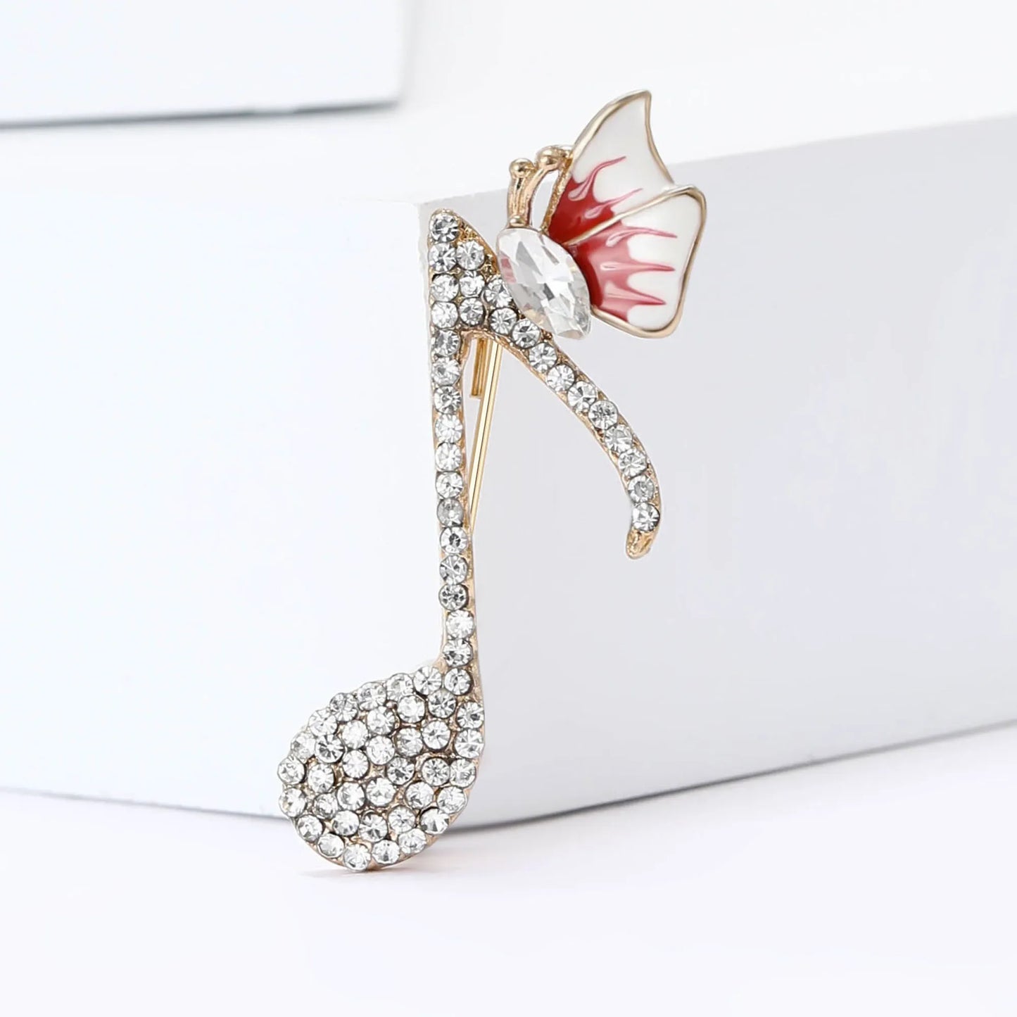 A sparkling gold-tone rhinestone butterfly pin with clear crystals and a red-and-white enamel butterfly for event party backpack decoration