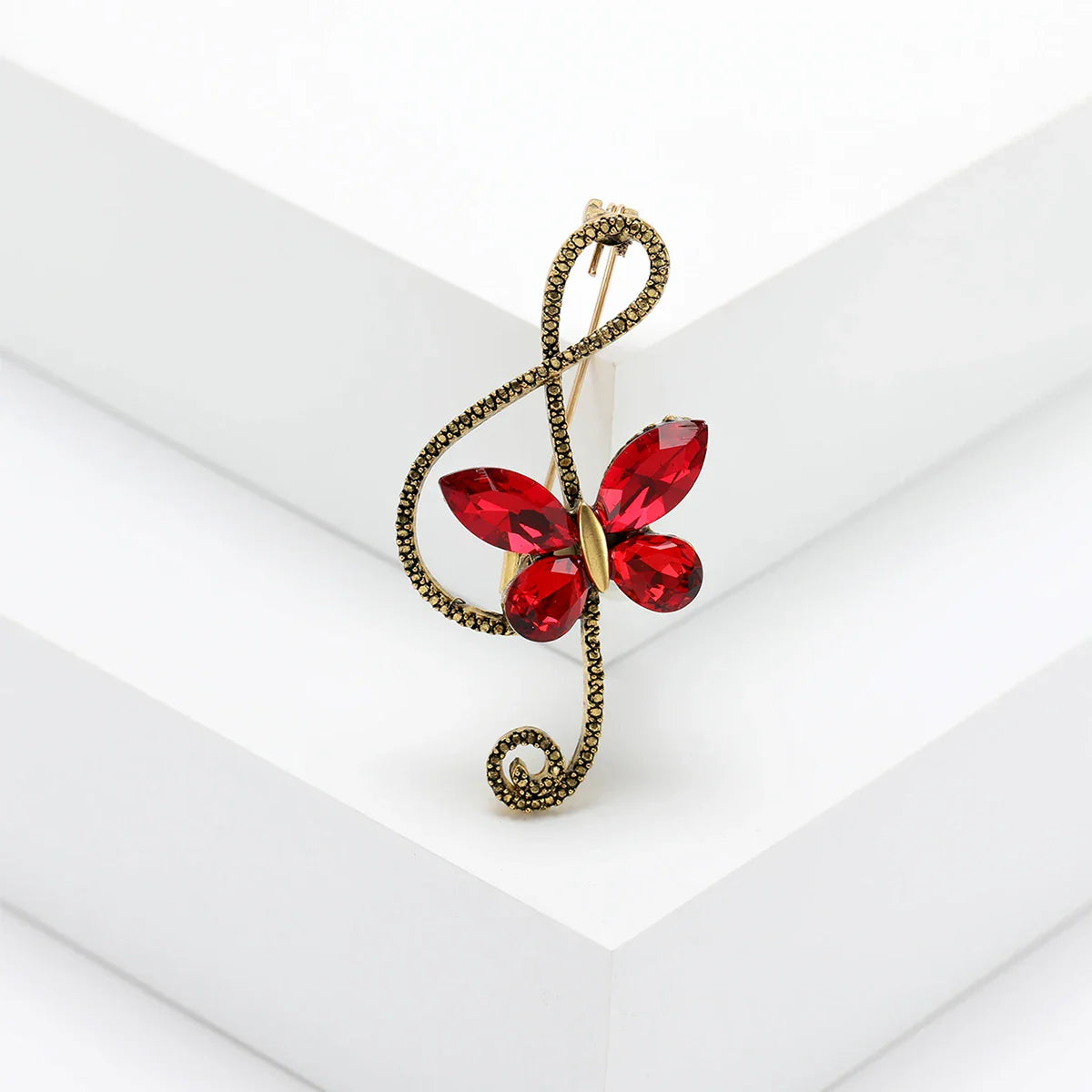 A red rhinestone butterfly pin with gold-toned metal wings and shiny glass musical note design for event party backpack