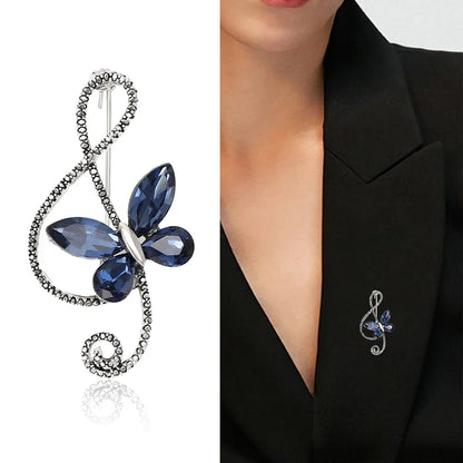 A sparkling navy blue rhinestone butterfly pin shaped like a shiny glass musical treble clef for event party backpack decor
