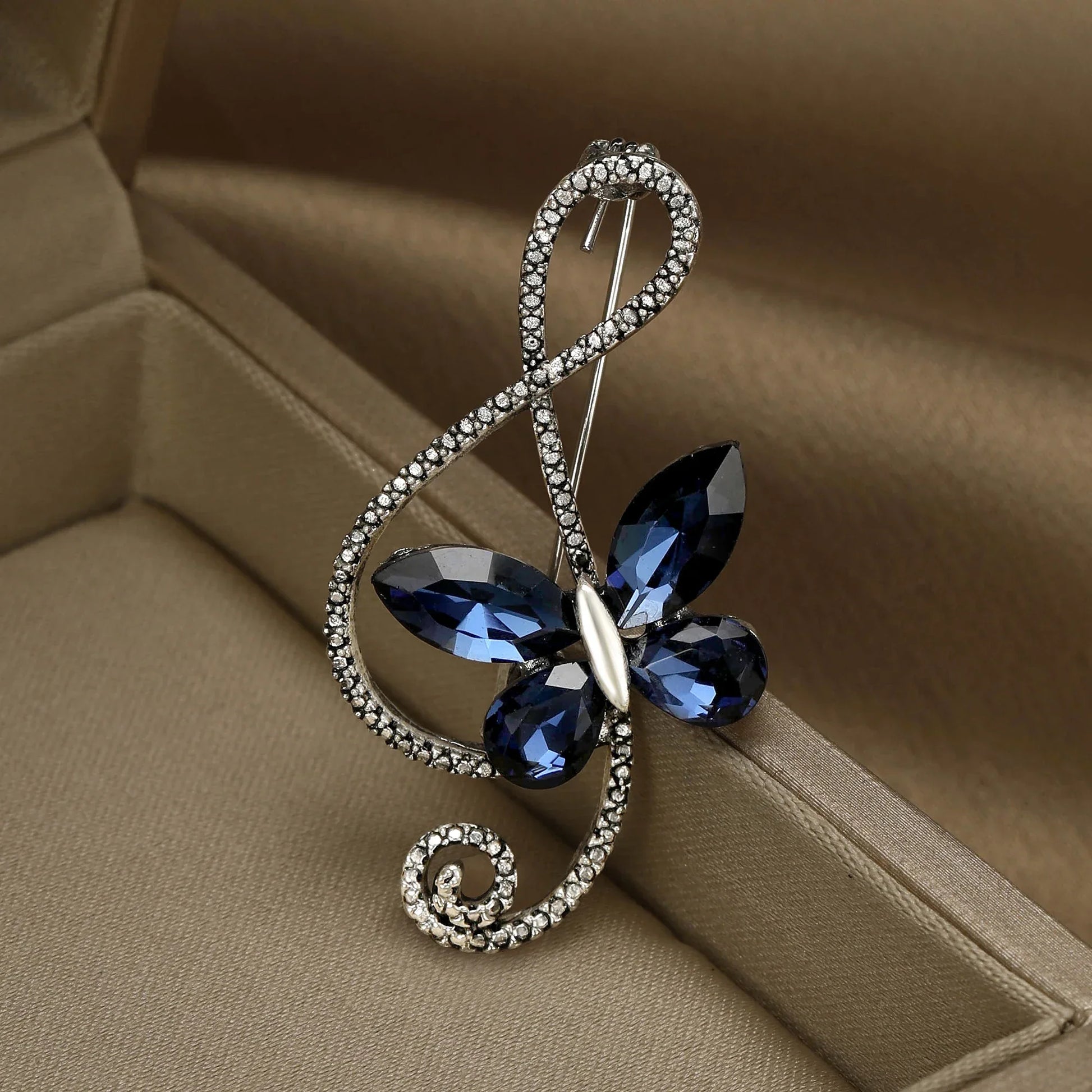 A sparkling silver rhinestone butterfly pin with deep blue shiny glass musical wings for event party backpack decor