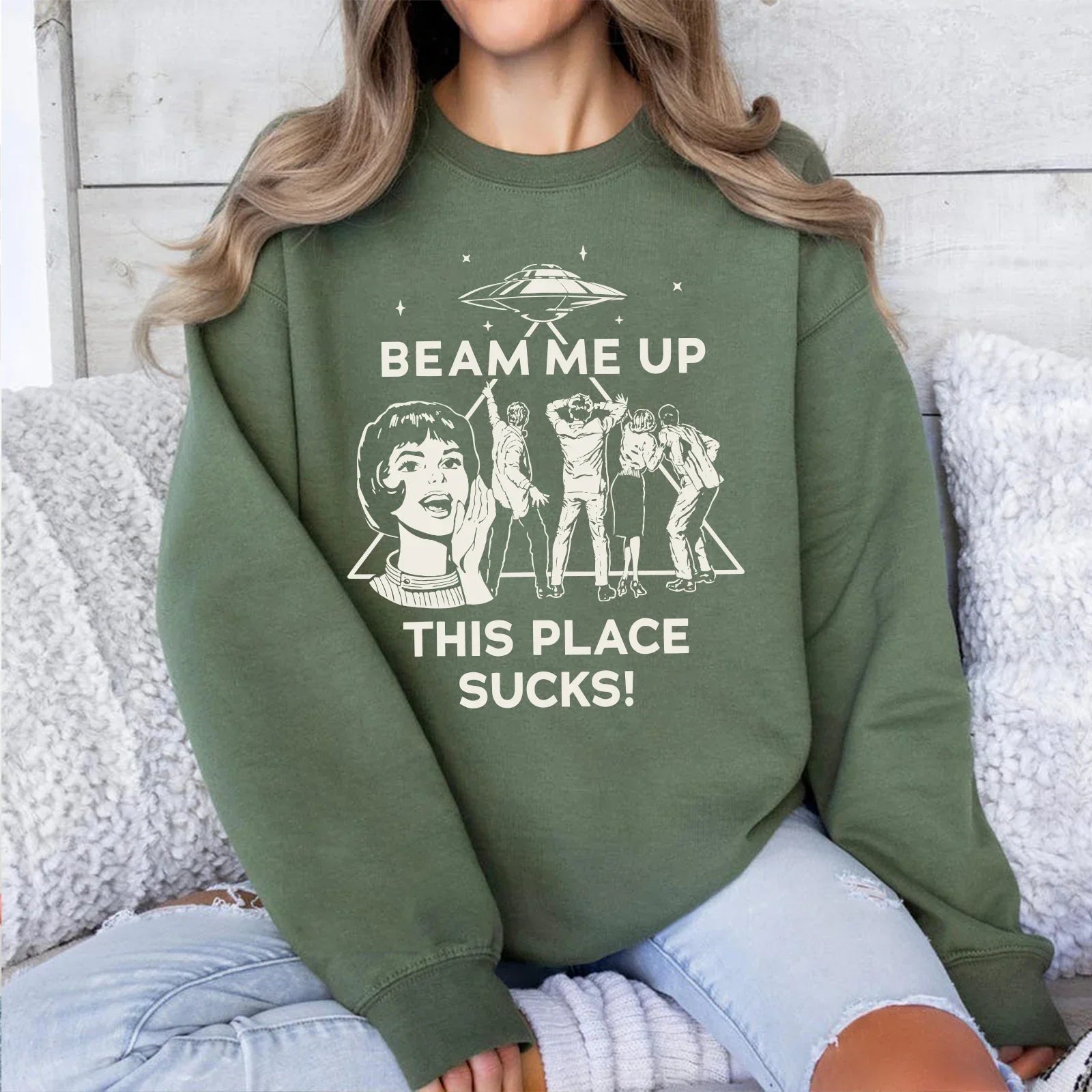 Olive green crewneck sweatshirt with white graphic of woman and five figures under text beam me up this place sucks man funny quote