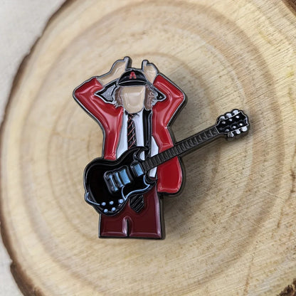 Red and black enamel pin featuring a stylized guitarist in a red jacket holding an electric guitar for music fans