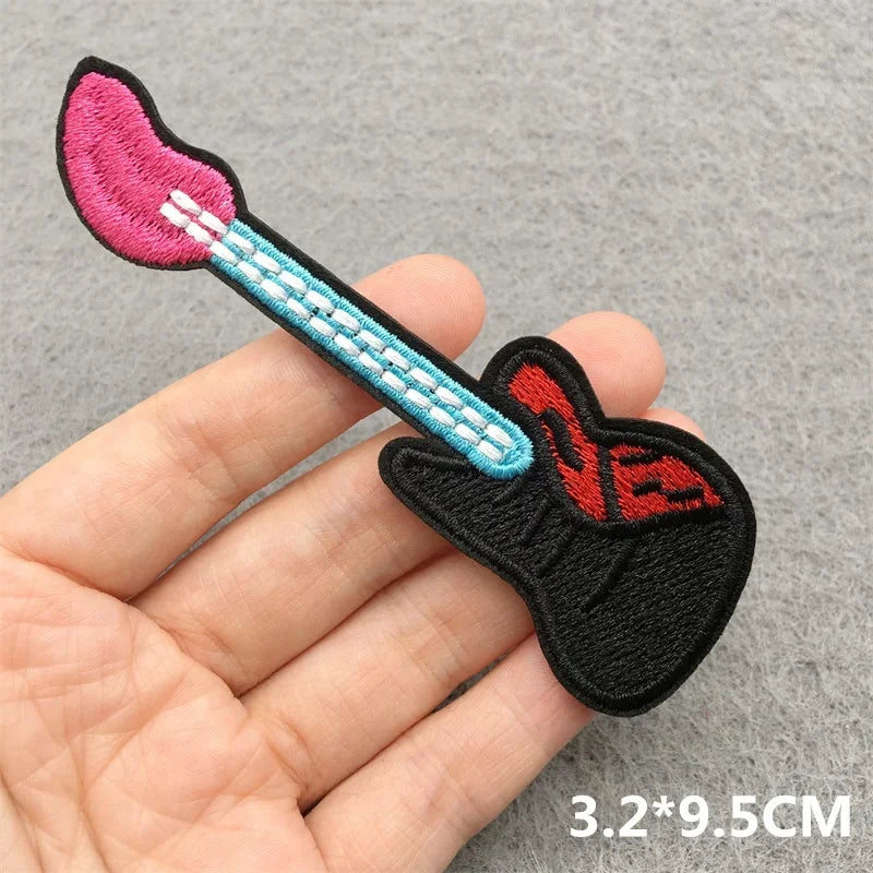 Vibrant rock music embroidered patch shaped like a guitar with pink pickguard and light blue neck for jacket jeans headset