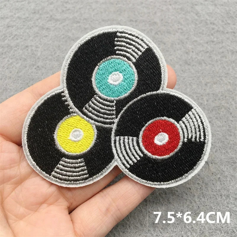 Handheld music embroidered patches featuring three stylized vinyl records in black teal yellow and red for jacket jeans headset