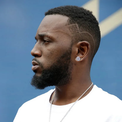 A man with a full beard wears a gold color round hip hop ice studded zircon earring and silver chain necklace