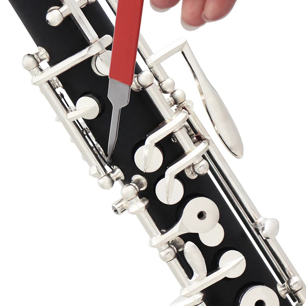 Black clarinet with silver keys being adjusted using a red-handled needle spring hook accessories double hooks repair tool