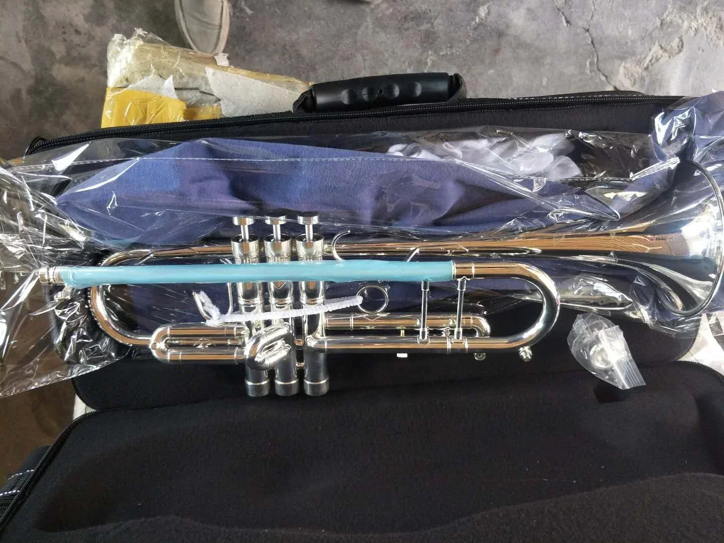 A seasound professional silver edward brass instrument trompeta with a light blue wrap resting in a black case