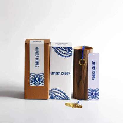 A polished wooden seventh chord wind chime with a golden ring and blue cord in branded meditation yoga japanese packaging