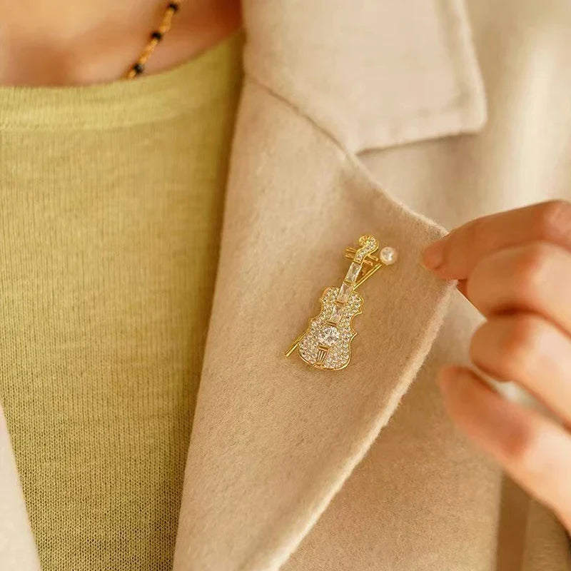 Delicate gold-tone violin brooch adorned with sparkling crystals and a small pearl for women music accessory